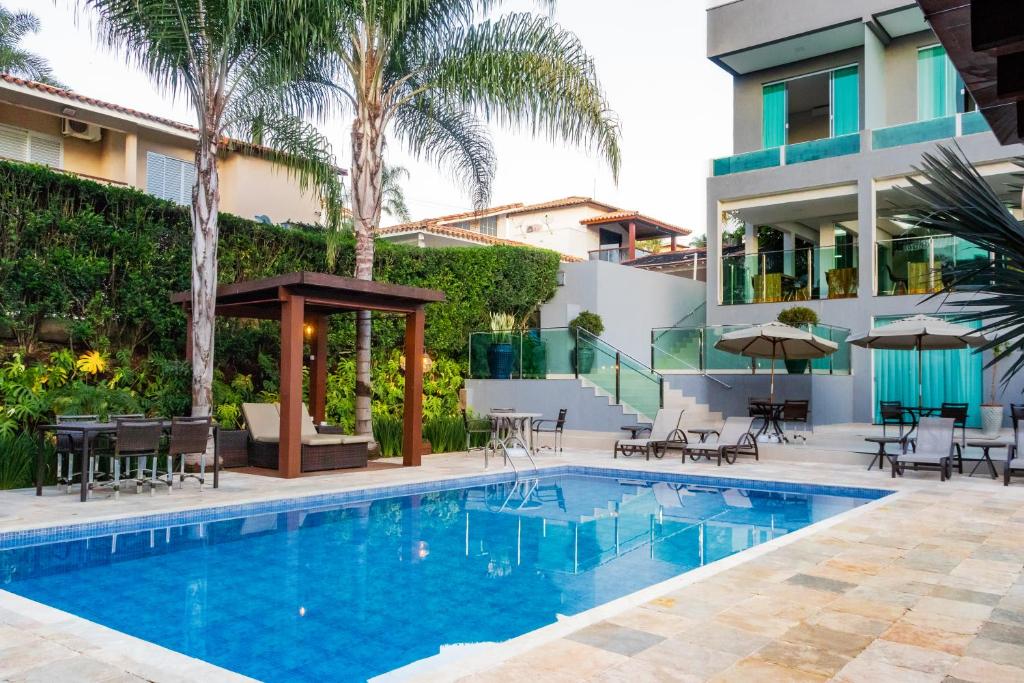 a swimming pool with tables and chairs next to a building at Escarpas Eco Village in Capitólio