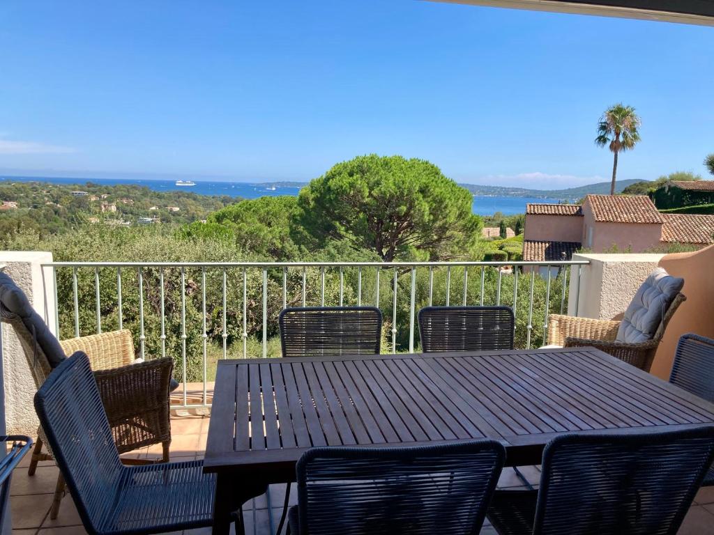 una mesa y sillas en un balcón con vistas al océano en Les Restanques 3120 vue mer 3 chambres en Grimaud