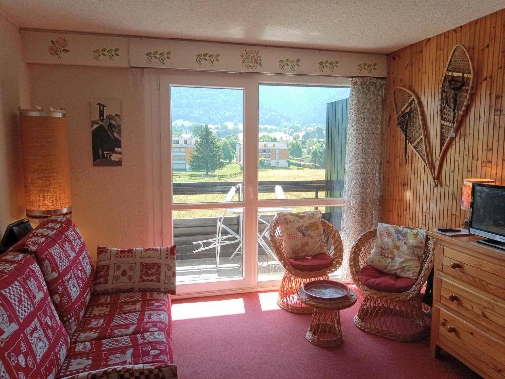 a living room with a couch and a large window at le Vercors en toute simplicite in Autrans