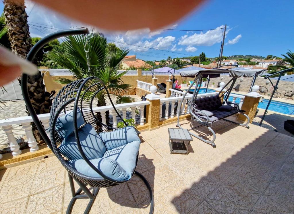 eine Schaukel mit Stühlen auf einer Terrasse neben einem Pool in der Unterkunft Carrio appartement 2 chambres in Calpe
