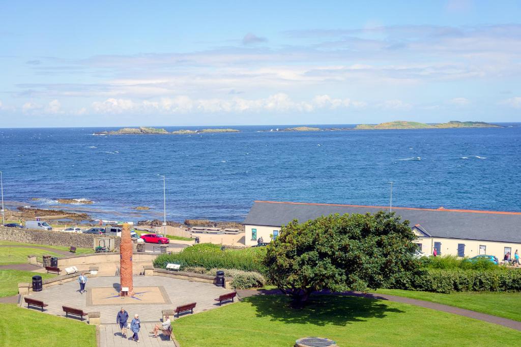 a group of people walking around a park next to the ocean at Portrush Atlantic Hotel in Portrush