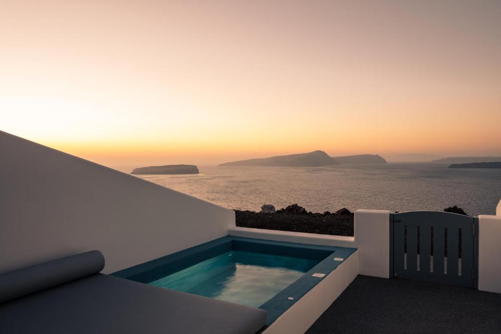 a terrace with a swimming pool and the ocean at El Destino Suites in Akrotiri