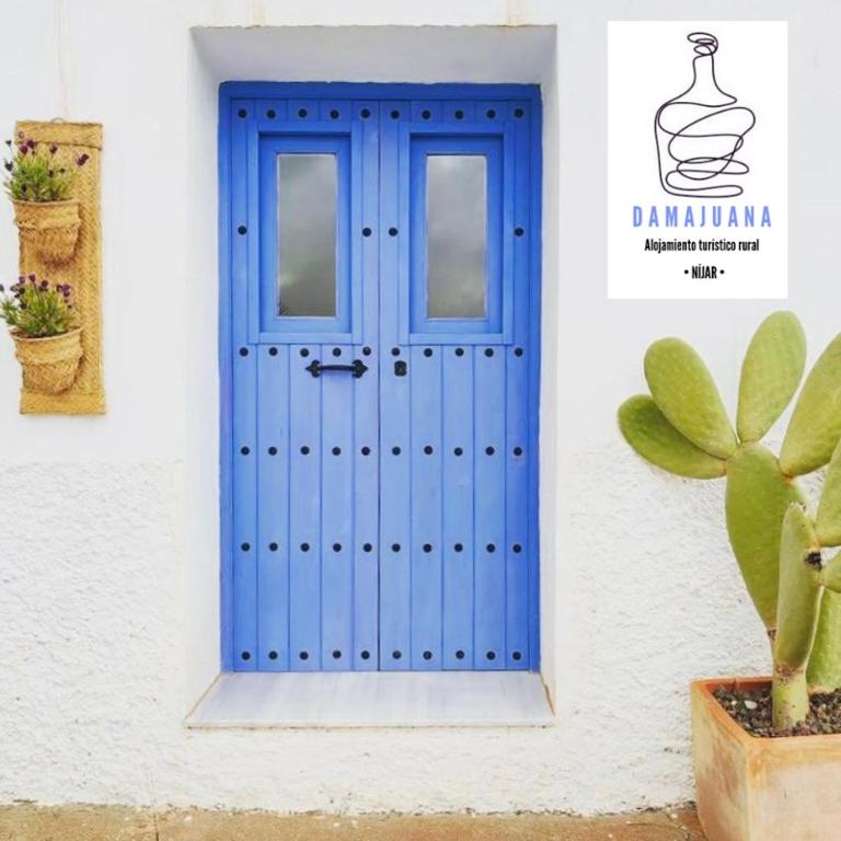 a blue door on a white building with a plant at Damajuana ll in Níjar
