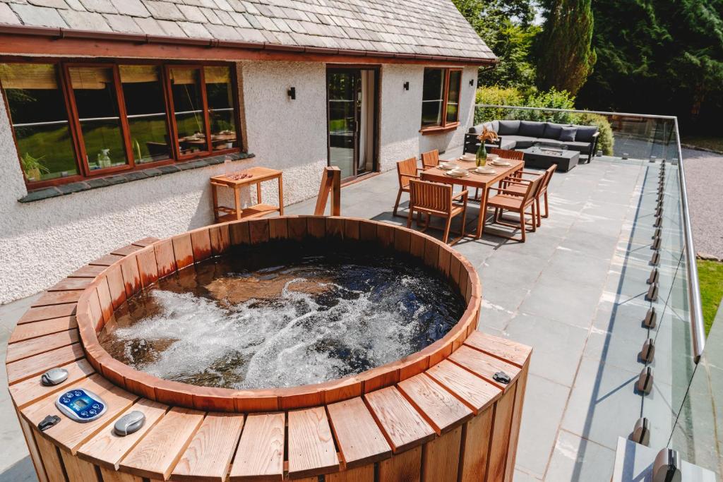 a patio with a hot tub with a table and chairs at Loughrigg Cottage in Ambleside
