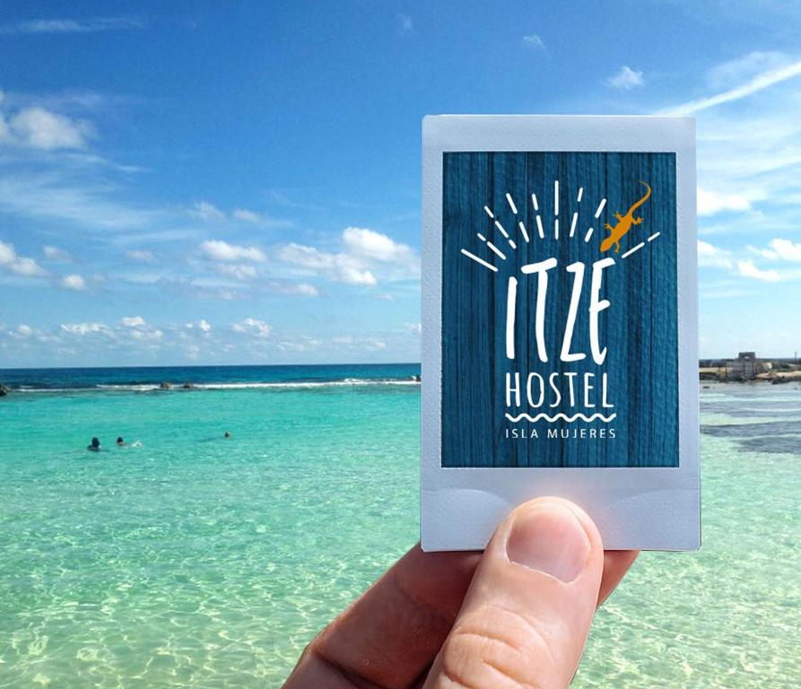 a person holding a book in front of the ocean at Itzé Hostel in Isla Mujeres