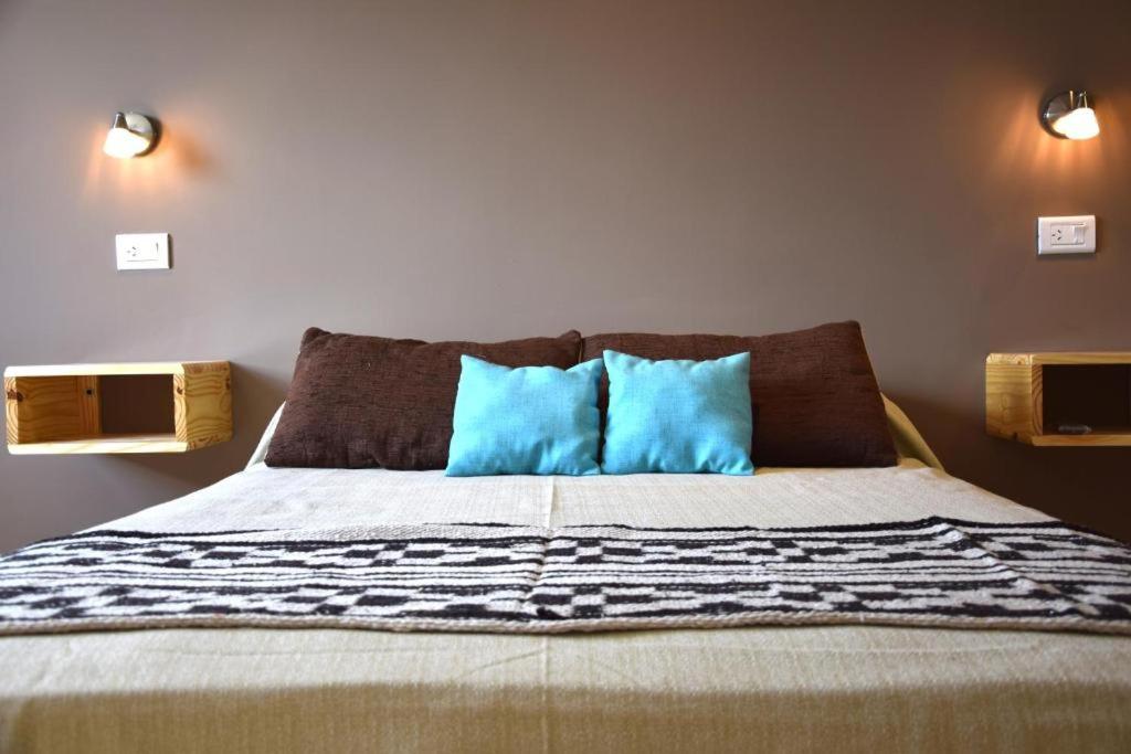 um quarto com uma cama com duas almofadas azuis em Amigo del Mundo Hostería y Apart Hotel em El Calafate