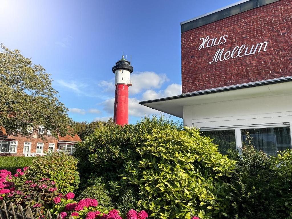 a red and white lighthouse in front of a building at Lighthousestudio & Spa in Wangerooge