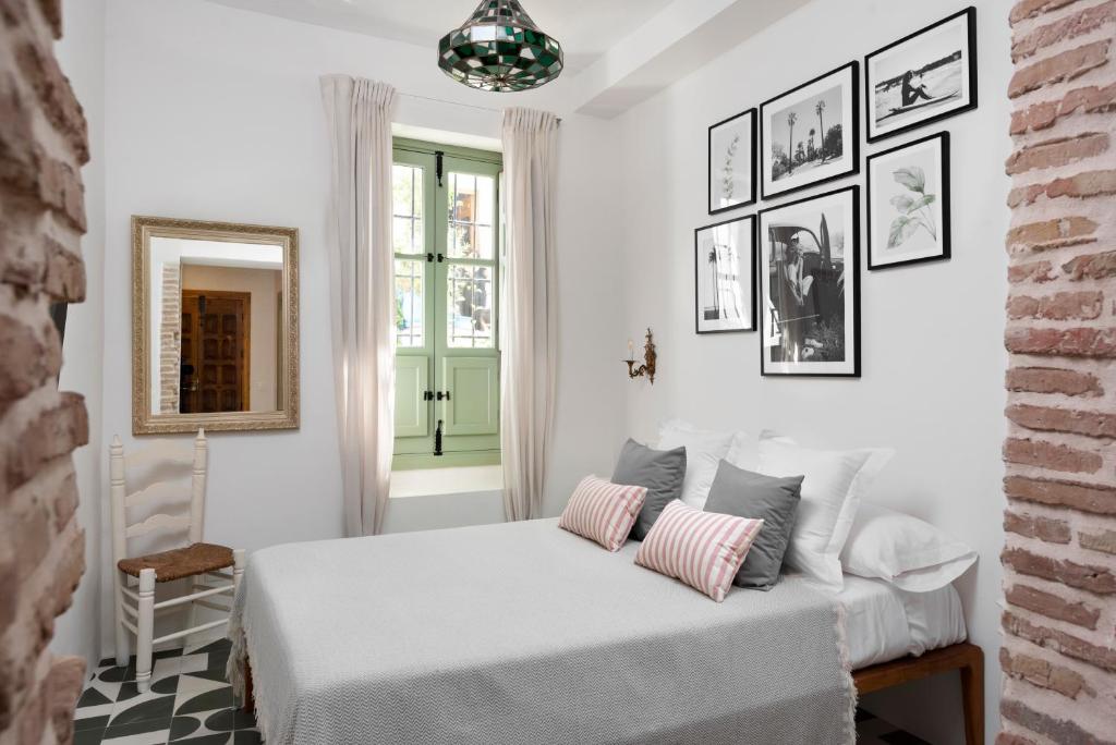 a white bedroom with a bed and a window at La AMARA Farah - en el casco antiguo de Frigiliana in Frigiliana