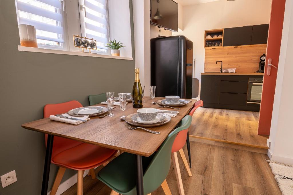 uma mesa de jantar com cadeiras e uma garrafa de vinho em Appartement Cosy avec Jardin au Centre Historique de Sélestat & Proche Europa-Park em Sélestat