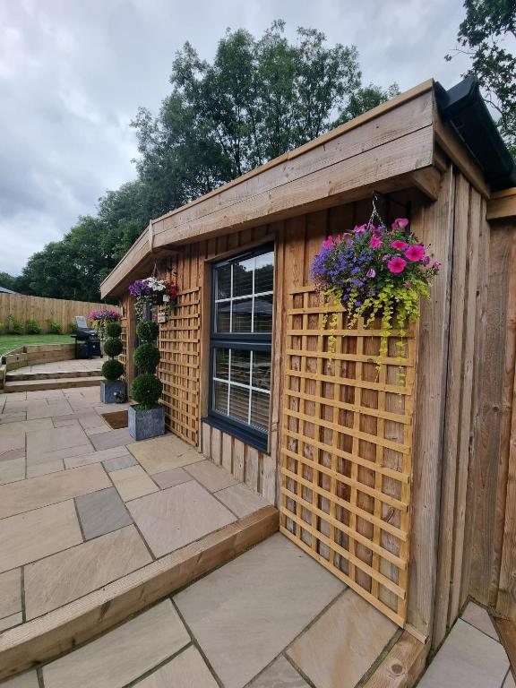 a wooden shed with flowers in it on a patio at Harewell wood cabin in Pateley Bridge