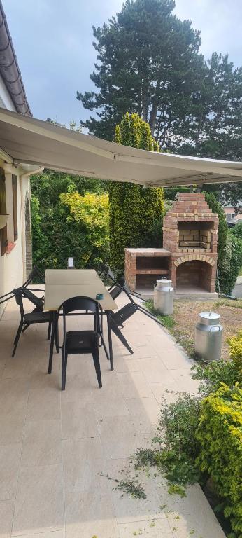 a patio with a picnic table and a fireplace at LE GALOPIN Etaples le Touquet in Étaples
