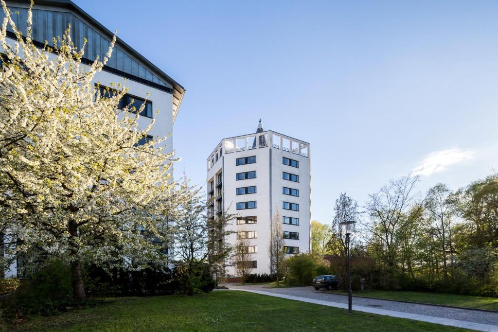 a tall white building next to a park with trees at Bildungszentrum Erkner in Erkner