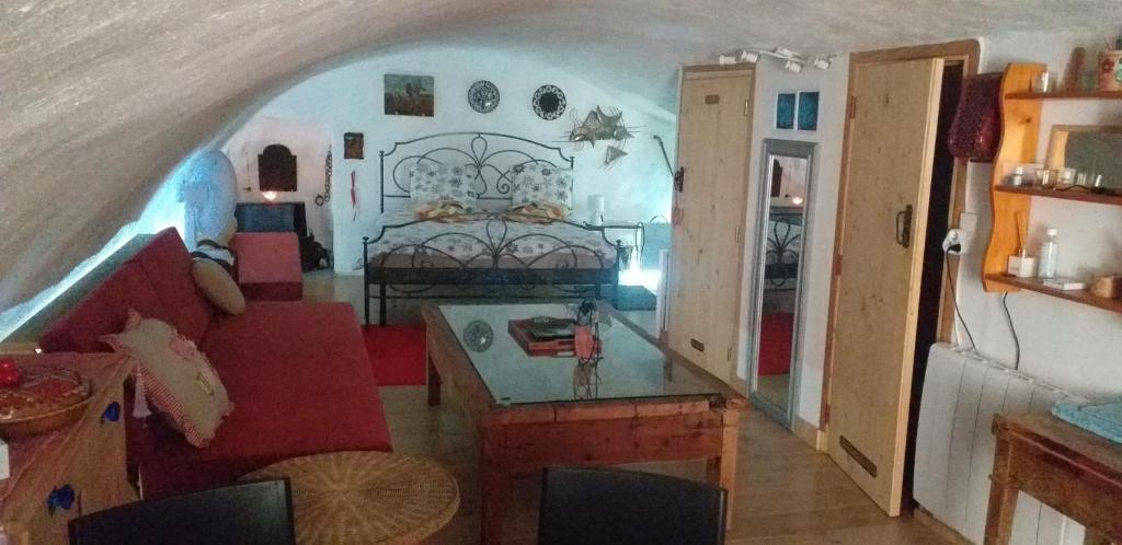 sala de estar con cama y sofá rojo en Studio atypique rue de Turin (ancienne étable de village), en Breil-sur-Roya