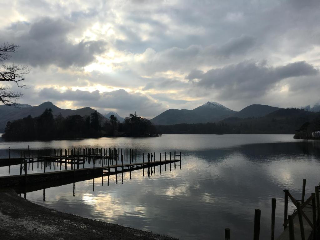 a dock on a lake with mountains in the background at Luxury Cottage, views of the Lakes with Hot Tub in Cockermouth