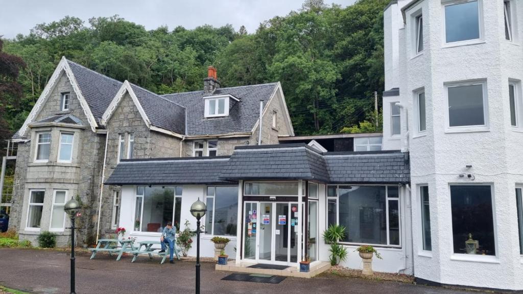 una casa con un salón acristalado delante de ella en The Lodge On The Loch Onich, en Onich