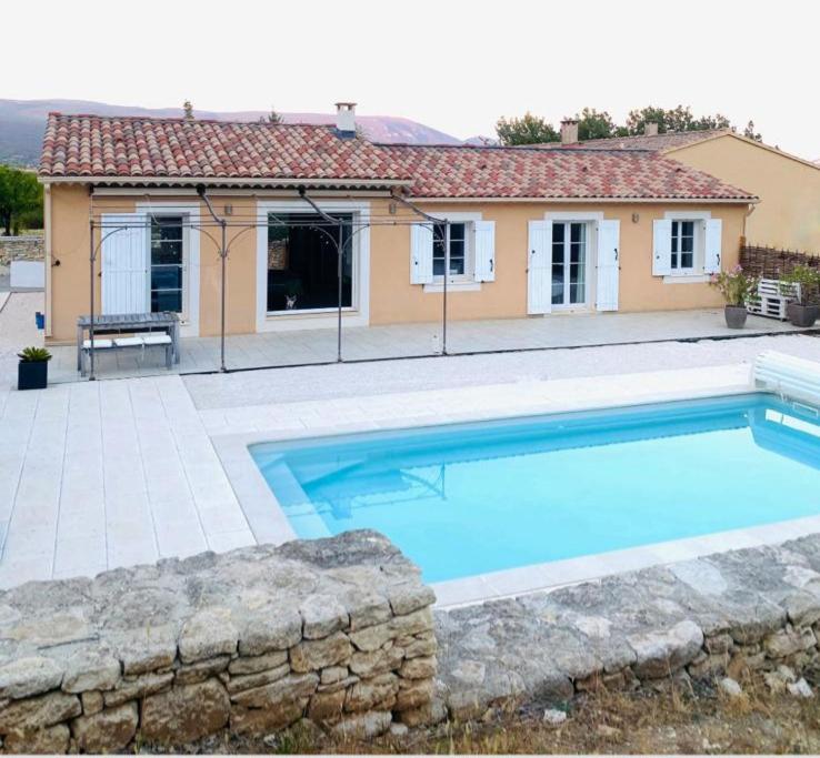 una grande piscina blu di fronte a una casa di Jolie maison de 110 m 2, pour 6 personnes, au calme, avec piscine a Les Cordiers