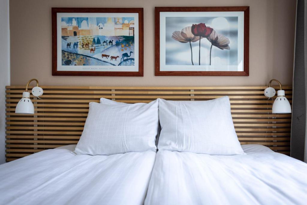 a bed with white pillows and two pictures on the wall at Miatorp Hotell in Helsingborg