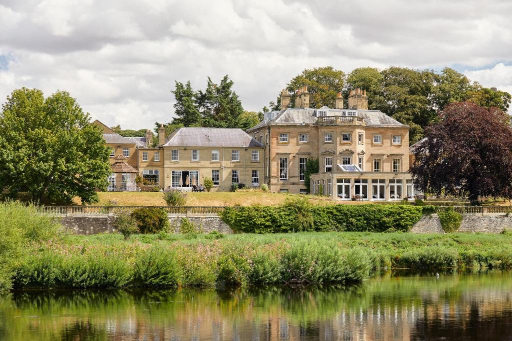 an old mansion next to a body of water at Ednam House Hotel in Kelso