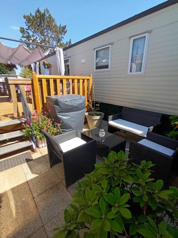 a patio with chairs and tables in front of a house at La Chanterie Agréable Mobil-Home Résidentiel Normand in Saint-Pair-sur-Mer