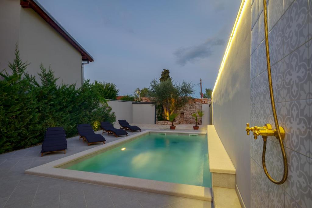 una piscina en un patio trasero con sillas azules junto a un edificio en Authentic Istrian Villa Stazione with Pool en Čabrunići