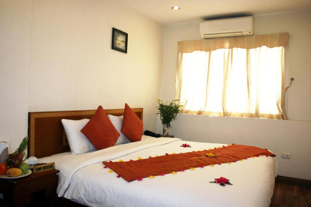 una camera da letto con un letto con cuscini arancioni e una finestra di Hanoi Charming House a Hanoi