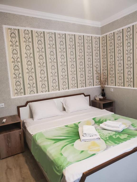 een slaapkamer met een groot bed en een groene deken bij Beehives in Koetaisi