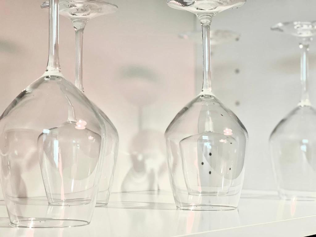 four empty wine glasses sitting on a table at M's Residences Maiolica in Trieste
