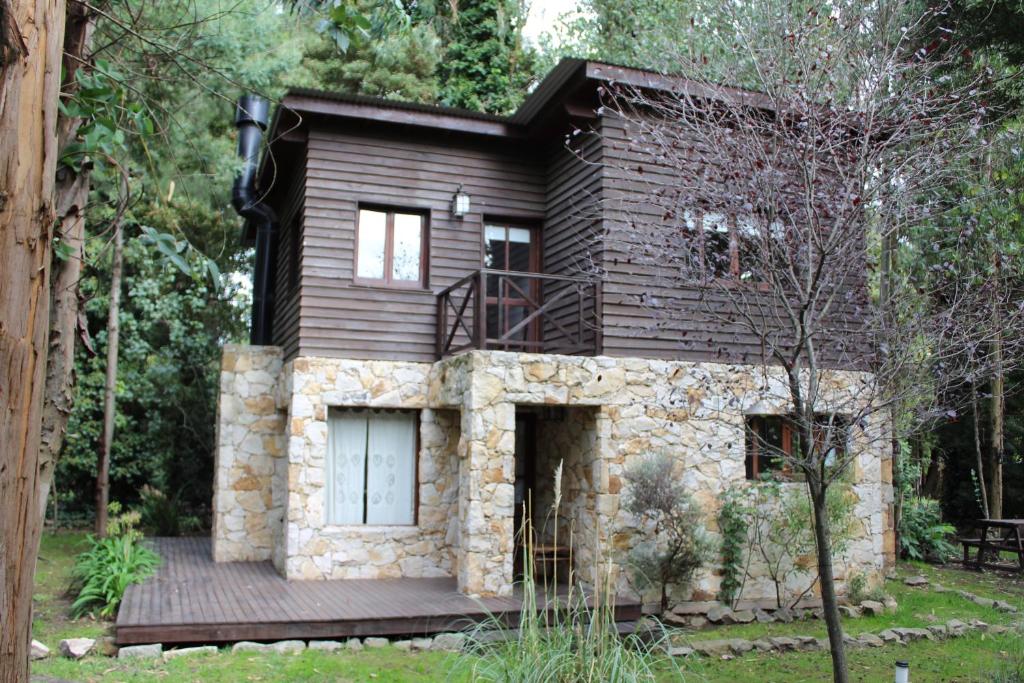 uma casa na floresta com um deque em Cabañas Las Olivas em Mar del Plata