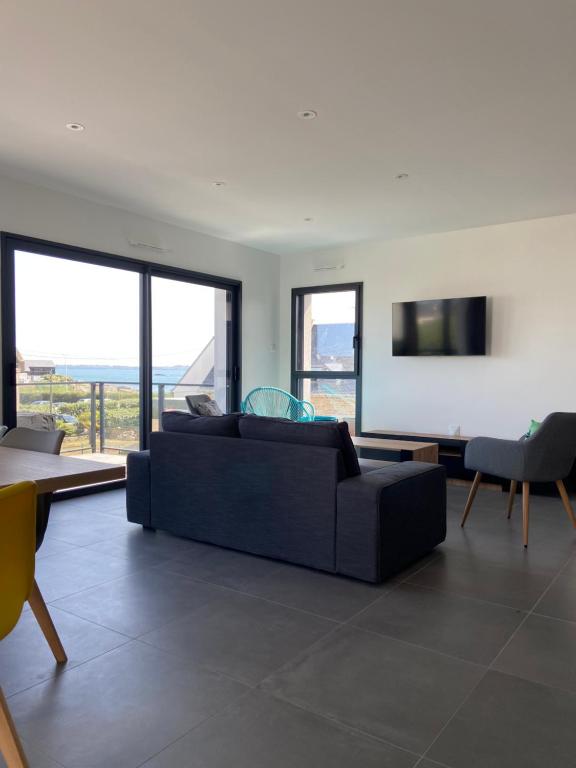 un salon avec un canapé noir et une table dans l'établissement Appartement avec terrasse vue mer, parking privé (lgt B), à Ploemeur