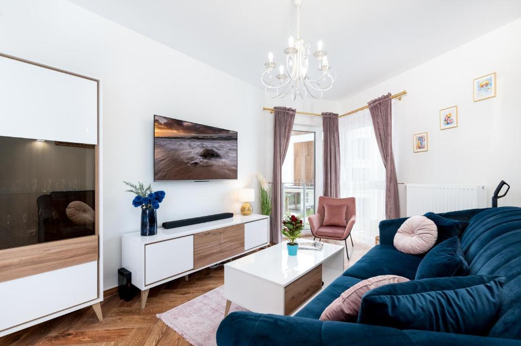 a living room with a blue couch and a tv at Apartament w Gąskach - Anielskie Wakacje in Gąski