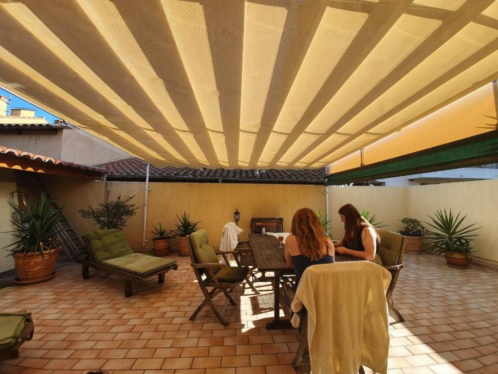 two women sitting at a table on a patio at Passerelle Opéra Perpignan in Perpignan