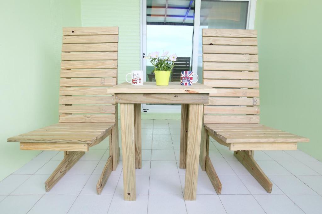 a wooden table with two chairs and a table with flowers at Edinburgh 16 Inn in Hengchun