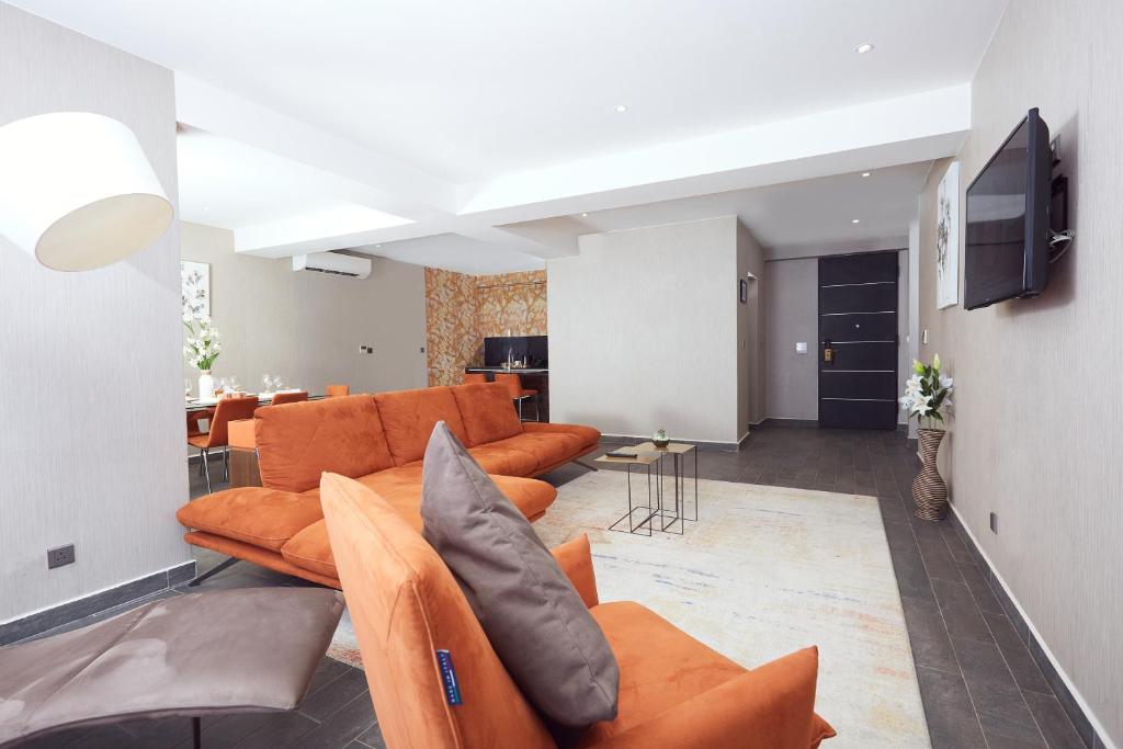 Bel Air Crest في آكرا: غرفة معيشة مع أرائك برتقالية وتلفزيون