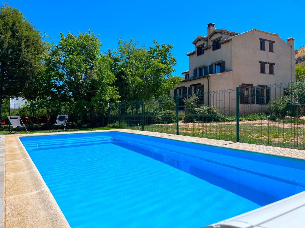 una piscina azul frente a una casa en HOTEL RURAL LA HUERTA, en Montejo de la Vega de la Serrezuela