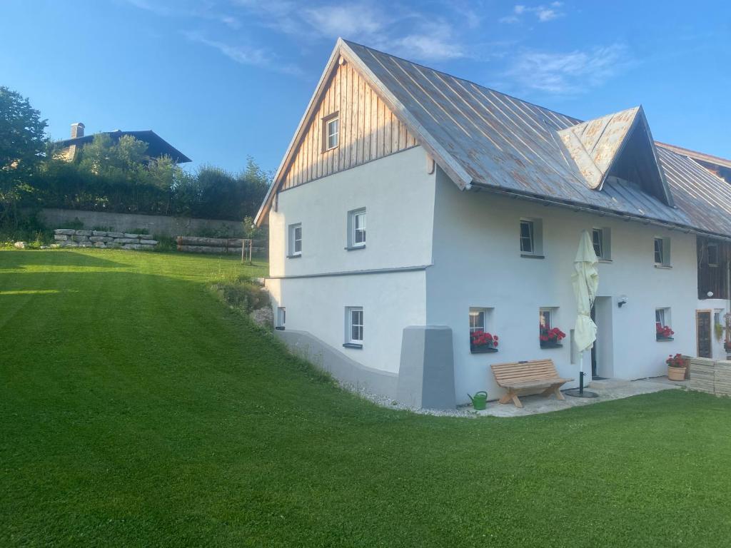 una casa blanca con un banco en un campo en Ferienhaus Krallinger, en Abtenau