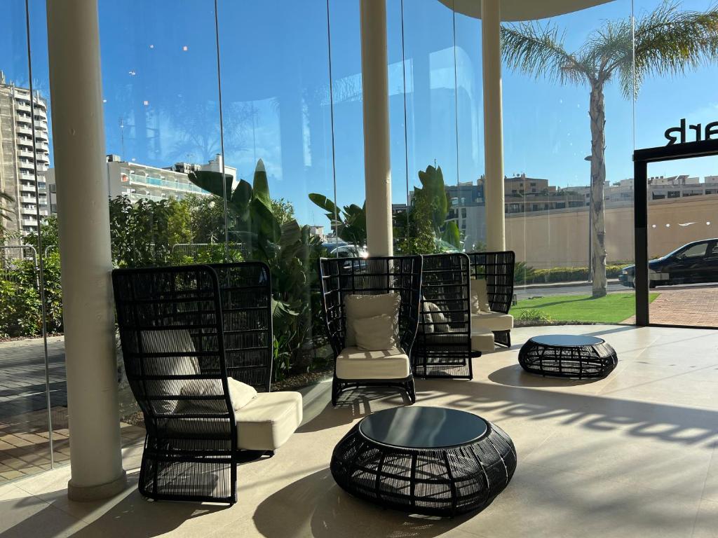 a group of chairs and tables in a building with windows at Hotel Primavera Park in Benidorm