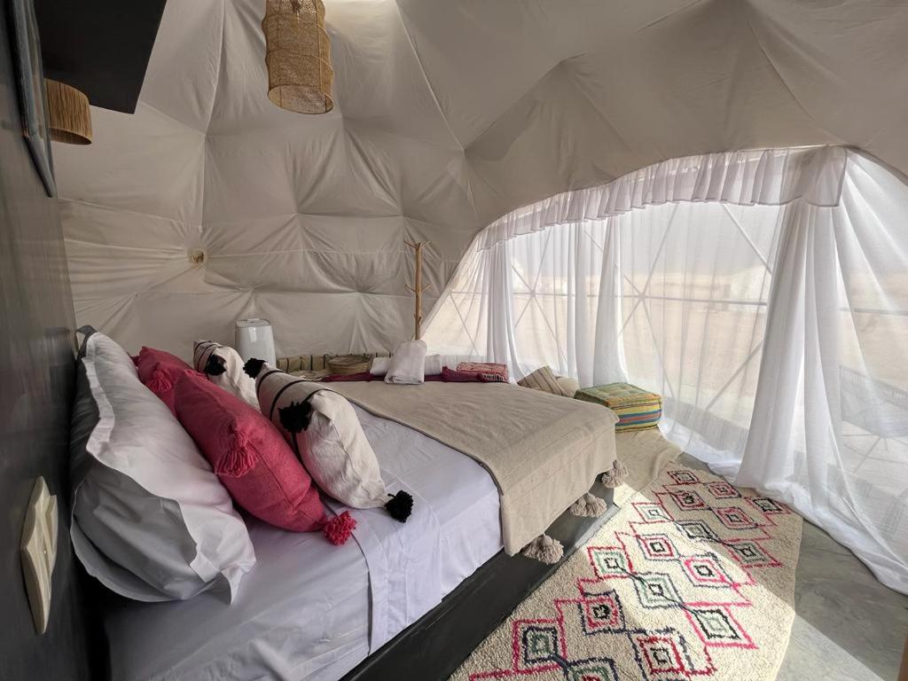 a bedroom with a tent with a bed with pillows at agafay valley in Marrakech