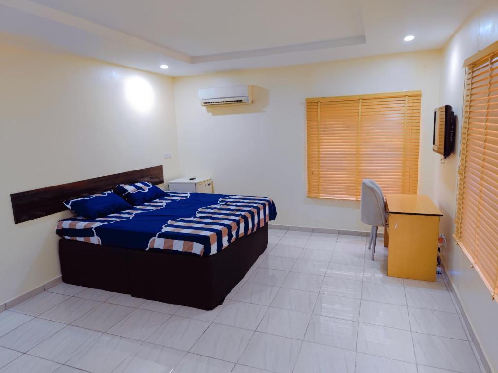 a bedroom with a bed and a desk in it at Highly Secured 24 Hours Electricity Apartment in Garki