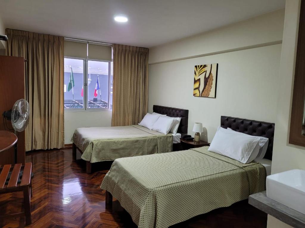 um quarto de hotel com duas camas e uma janela em Hostal Solari em Trujillo
