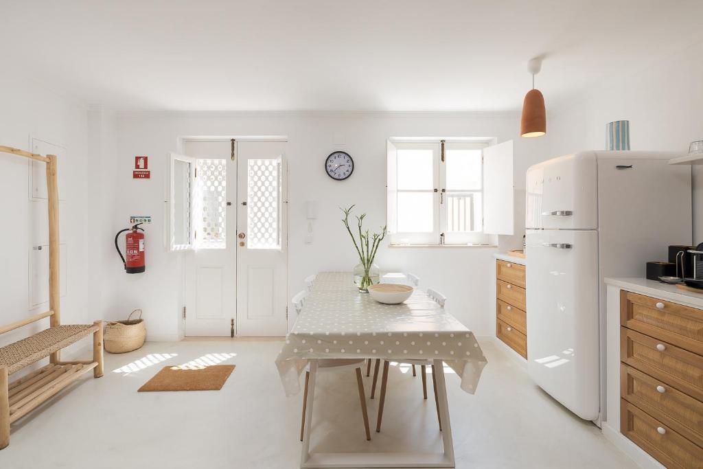 a white kitchen with a table and a refrigerator at Travessa's House in Olhão