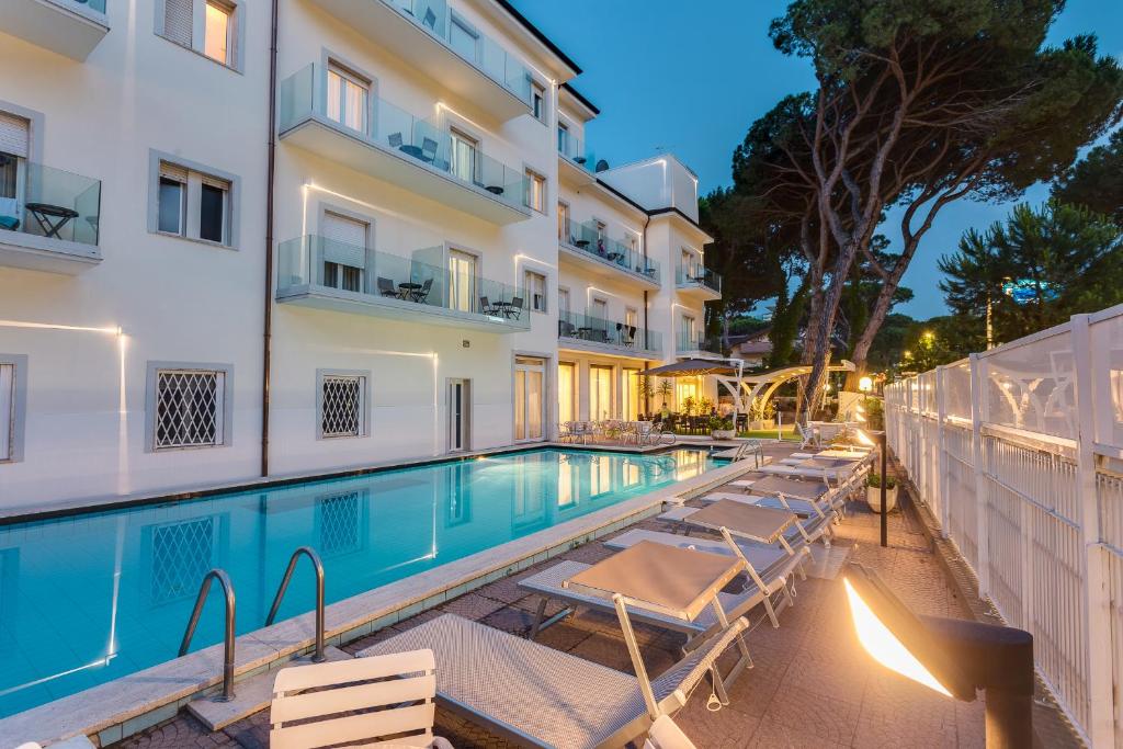 a swimming pool with lounge chairs next to a building at Hotel Vela in Milano Marittima