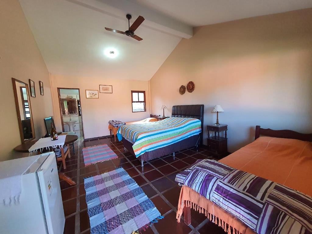 1 dormitorio con 2 camas y ventilador de techo en Fazenda Serra que Chora - Pousada e Restaurante, en Itanhandu