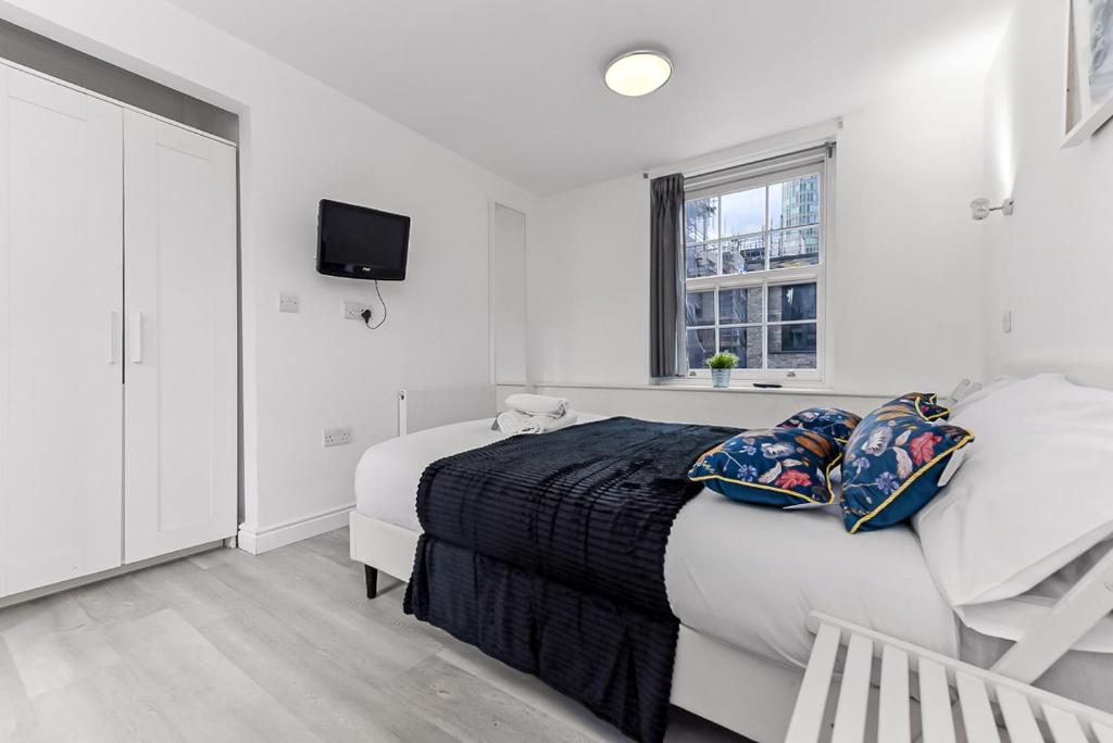 a white bedroom with a bed and a window at Charlotte Street Rooms by News Hotel in London