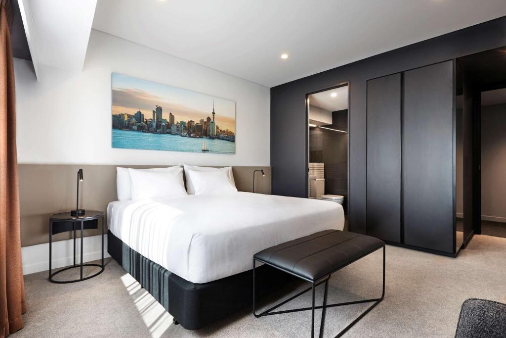 a bedroom with a large white bed and a stool at Travelodge Hotel Auckland Wynyard Quarter in Auckland