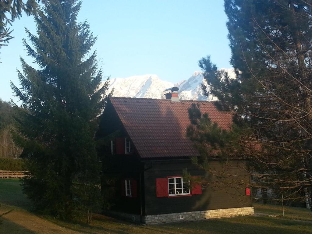 a house with a snow covered mountain in the background at Heidi's Häuschen in Bad Mitterndorf