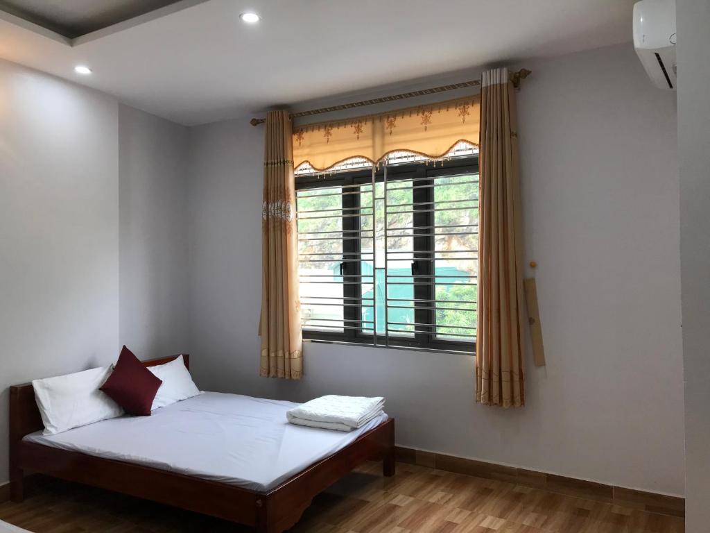 um quarto com uma cama e uma janela em Nhà Nghỉ Minh Hảo em Làng Môn