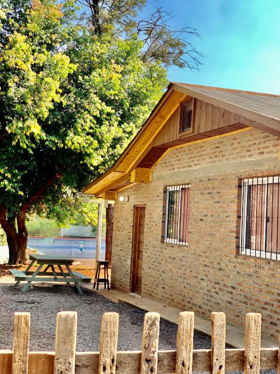 a wooden fence in front of a building with a picnic table at Cabañas CheRu 5 in Posadas