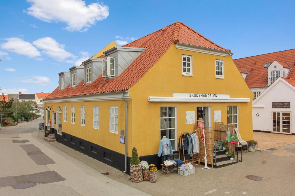 un edificio amarillo al lado de una calle en Skudehandelen. en Lønstrup