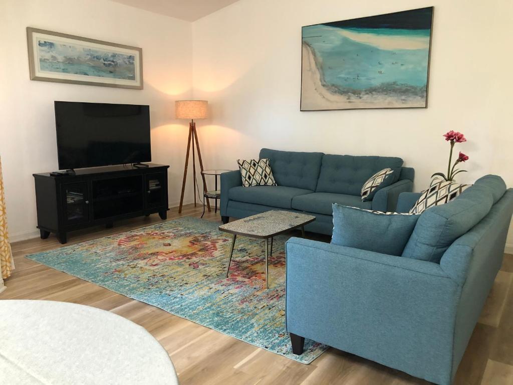 uma sala de estar com um sofá azul e uma televisão em o BEAUTIFUL CONDO MINUTES FROM GORGEOUS CLEARWATER BEACHES o em Clearwater