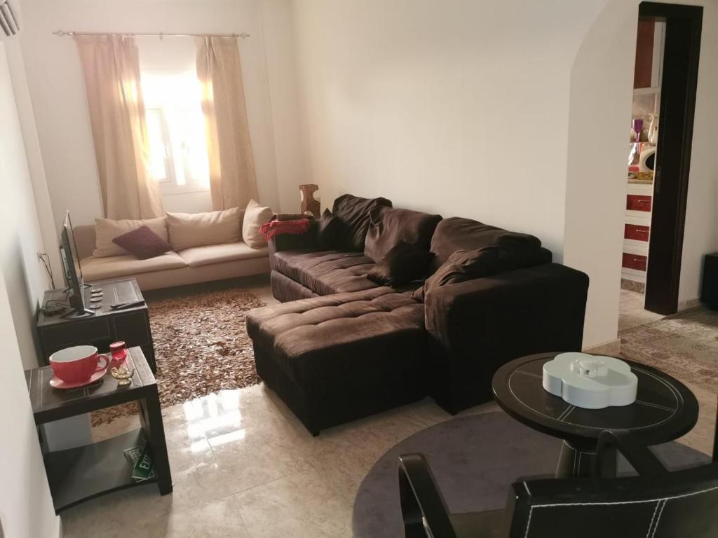 a living room with a brown couch and a table at Seeb Lux Apartment in Muscat
